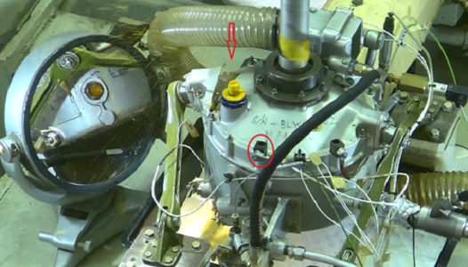 Figure 1.  The cracked gearbox with the casing crack indicated by the red arrow. The Ring-Front vibration RF-2 sensor is in the red circle shown as an orientation reference. A mirror was on the left hand side of the picture.