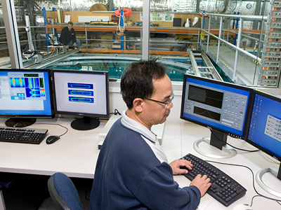 An image of a DSTG scientist at a computer, with the underwater facility in the background.